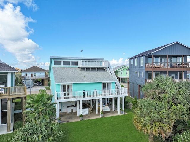 back of house featuring a carport, a balcony, a patio area, and a lawn