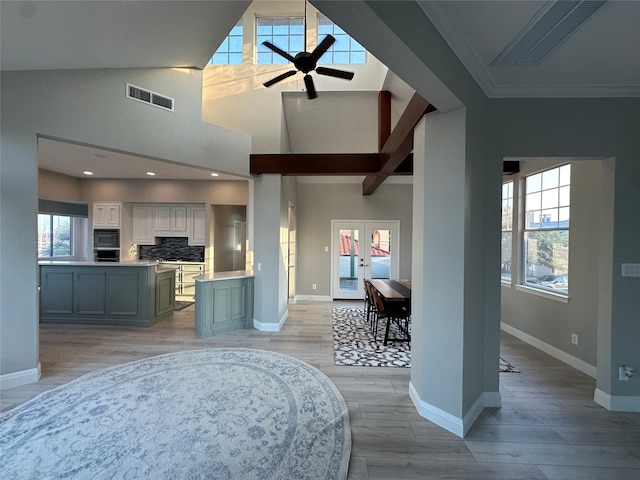 interior space with a wealth of natural light, white cabinets, light hardwood / wood-style flooring, decorative backsplash, and ceiling fan