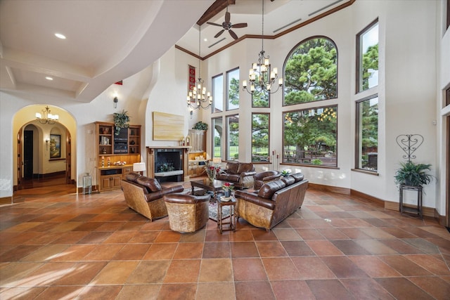 living room featuring arched walkways, ceiling fan with notable chandelier, recessed lighting, baseboards, and a towering ceiling