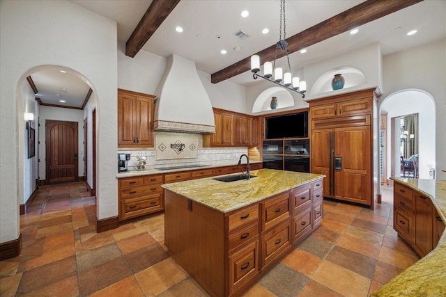 kitchen featuring black electric stovetop, a sink, arched walkways, custom range hood, and paneled fridge