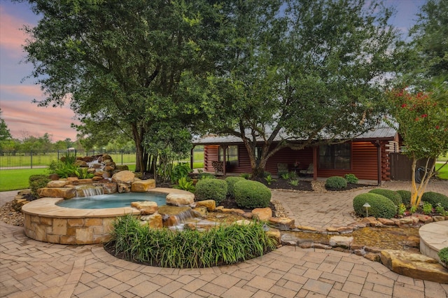 yard at dusk featuring a patio area, an in ground hot tub, and fence