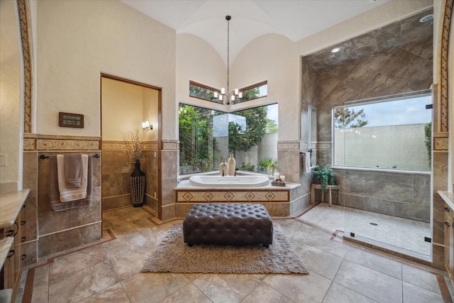 bathroom featuring tile walls, wainscoting, an inviting chandelier, and a garden tub
