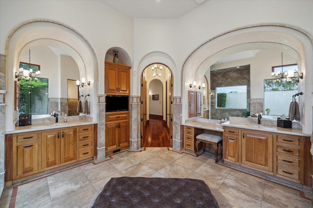 full bath with a sink, two vanities, and a chandelier