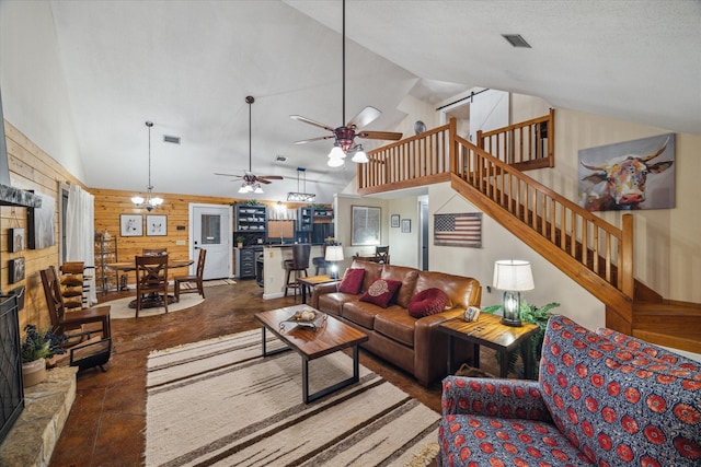 living room featuring wooden walls, finished concrete flooring, high vaulted ceiling, stairs, and a ceiling fan