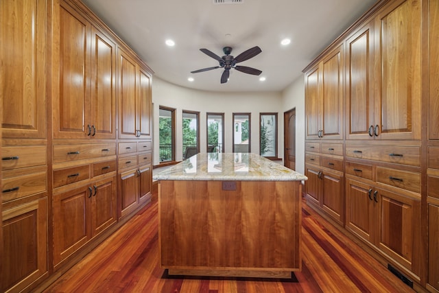 kitchen with a kitchen island, light stone countertops, dark wood-style floors, recessed lighting, and a ceiling fan