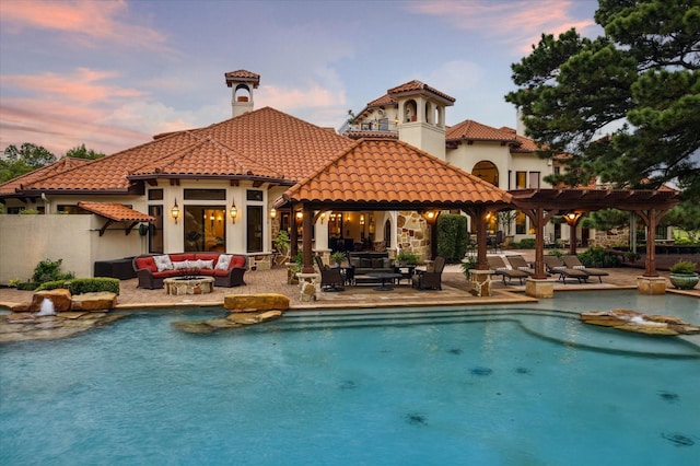 back of property at dusk with an outdoor hangout area, a pergola, a tile roof, and an outdoor pool