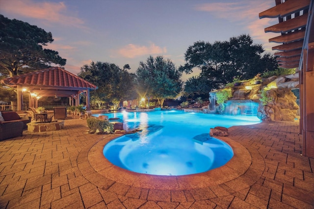 pool at dusk featuring a gazebo, a hot tub, an outdoor pool, and a patio