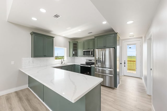 kitchen with kitchen peninsula, sink, light hardwood / wood-style flooring, and stainless steel appliances