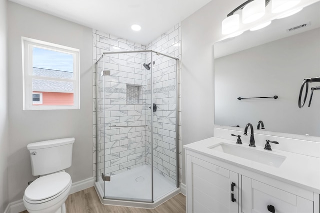 bathroom featuring wood-type flooring, vanity, toilet, and an enclosed shower