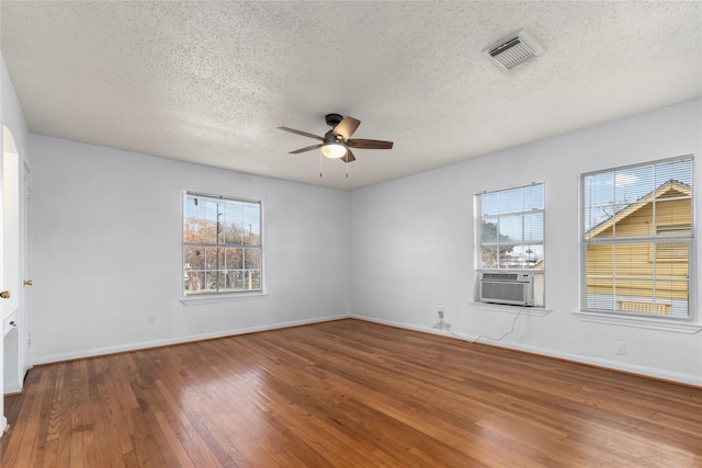 spare room featuring cooling unit, ceiling fan, hardwood / wood-style floors, and a textured ceiling