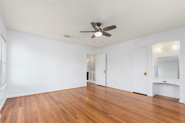 unfurnished bedroom featuring ceiling fan, hardwood / wood-style flooring, and a textured ceiling