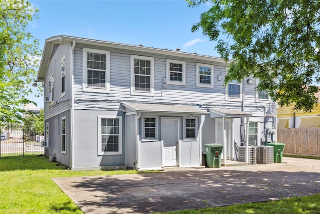 front facade featuring cooling unit and a front lawn