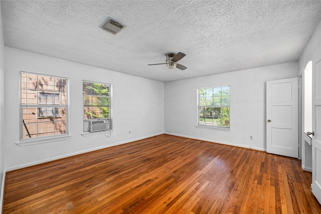 empty room featuring ceiling fan, cooling unit, a textured ceiling, and hardwood / wood-style floors