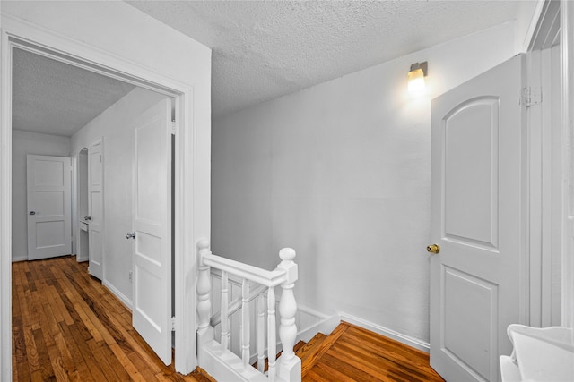 corridor with a textured ceiling and wood-type flooring