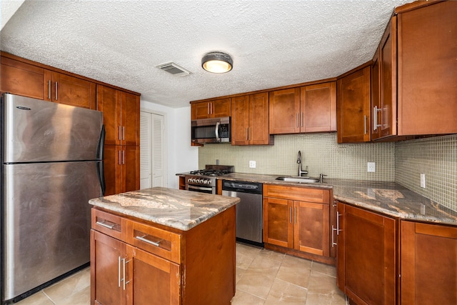 kitchen with appliances with stainless steel finishes, sink, dark stone counters, and a kitchen island