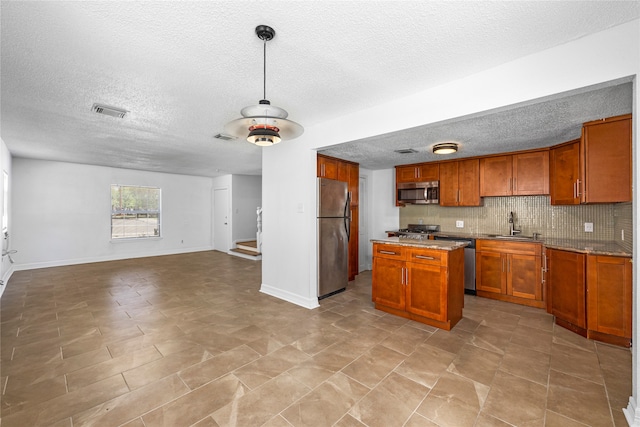 kitchen with sink, tasteful backsplash, a kitchen island, a textured ceiling, and stainless steel appliances