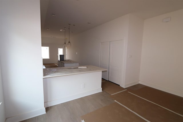 kitchen with decorative light fixtures, kitchen peninsula, and hardwood / wood-style flooring