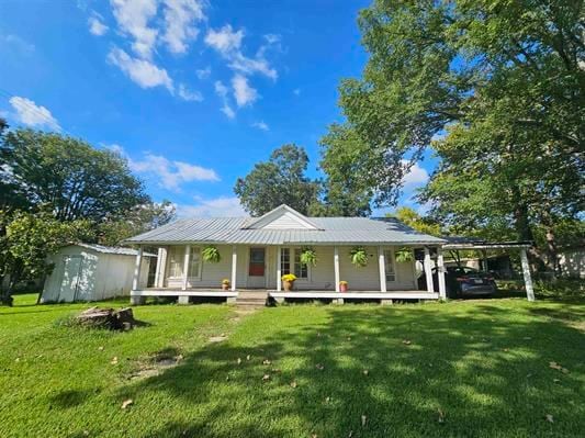 view of front facade featuring a shed, a carport, a porch, and a front yard