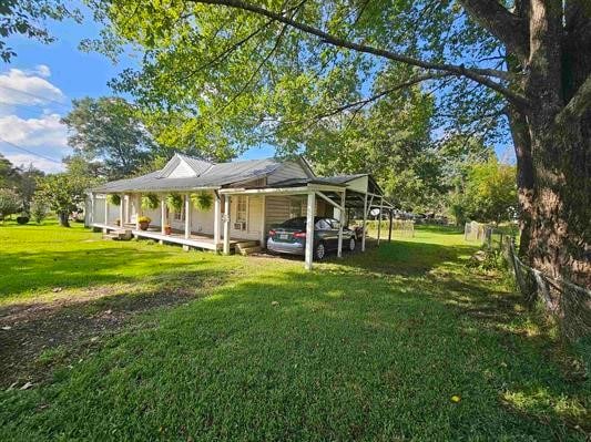 rear view of property featuring a carport, a porch, and a yard