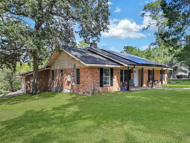307 N Bayou Bend Dr, Baytown, TX 77521 - single story home with a porch, brick siding, a front yard, solar panels, and a chimney