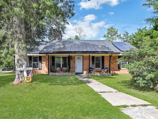 ranch-style house featuring a porch, a front lawn, and solar panels