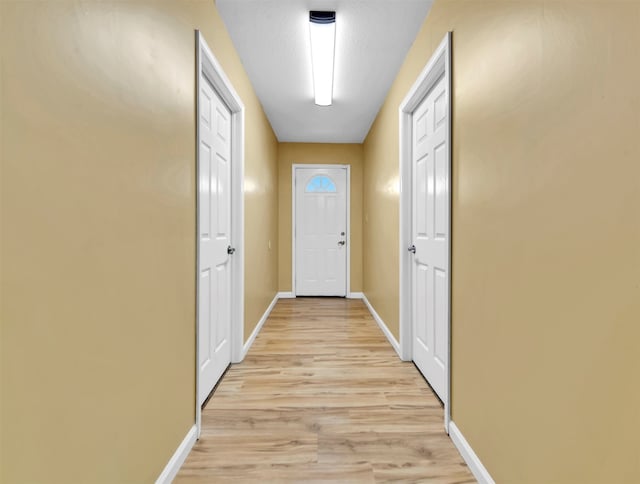 hallway featuring light wood-type flooring and a textured ceiling