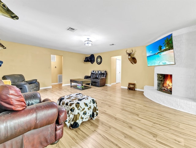 living room with a brick fireplace and light hardwood / wood-style flooring