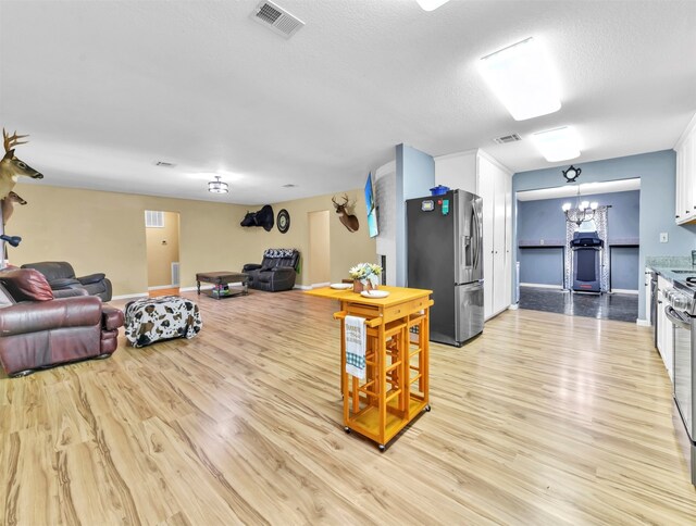 living room with a textured ceiling, light hardwood / wood-style floors, sink, and a chandelier