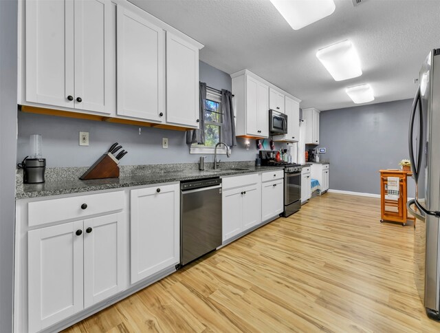 kitchen with light wood-type flooring, white cabinetry, sink, and stainless steel appliances