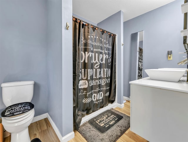 bathroom with walk in shower, hardwood / wood-style floors, vanity, and toilet