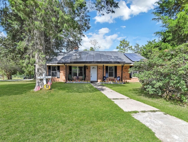 ranch-style home with a front yard, solar panels, and covered porch