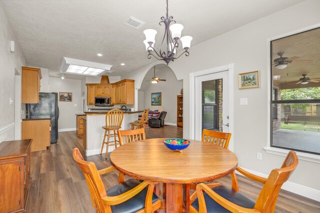 dining room featuring a textured ceiling, ceiling fan with notable chandelier, and dark hardwood / wood-style floors