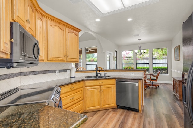 kitchen featuring appliances with stainless steel finishes, light hardwood / wood-style floors, kitchen peninsula, decorative light fixtures, and sink