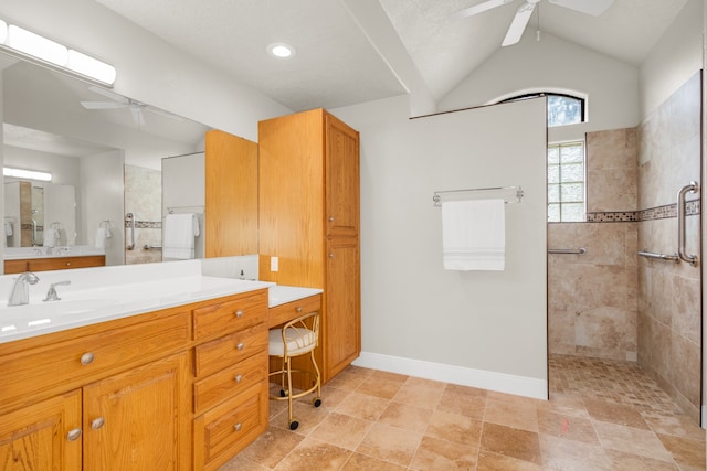 bathroom with ceiling fan, vanity, lofted ceiling, and a tile shower