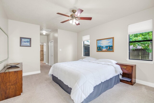 bedroom featuring light carpet, a closet, ceiling fan, and multiple windows