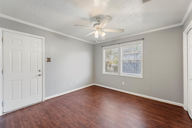 empty room featuring ornamental molding, ceiling fan, dark wood-type flooring, and a textured ceiling