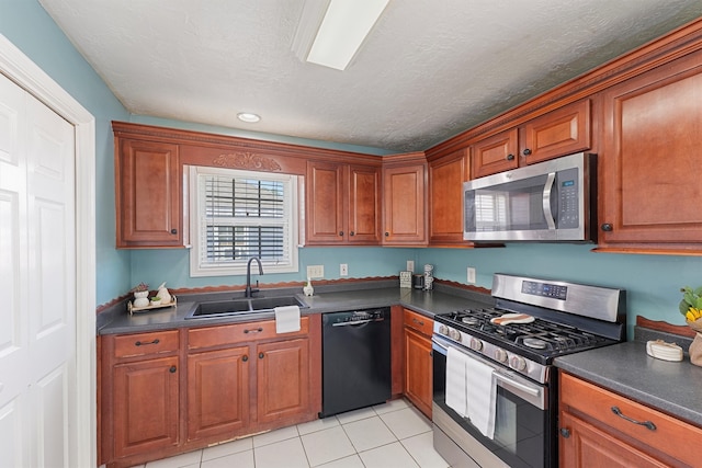 kitchen featuring appliances with stainless steel finishes, light tile patterned flooring, sink, and a textured ceiling