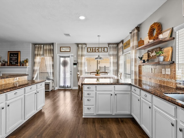 kitchen featuring a peninsula, white cabinets, open shelves, tasteful backsplash, and dark wood finished floors