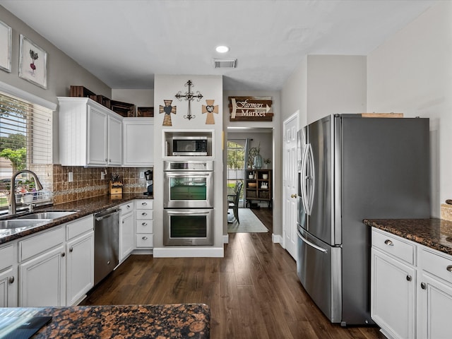 kitchen featuring stainless steel appliances, a sink, visible vents, white cabinetry, and tasteful backsplash