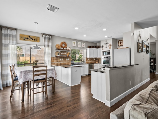 kitchen with visible vents, dark countertops, appliances with stainless steel finishes, a peninsula, and open shelves