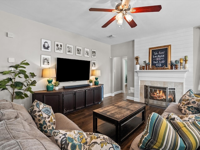 living area featuring ceiling fan, a fireplace, visible vents, and dark wood-style flooring