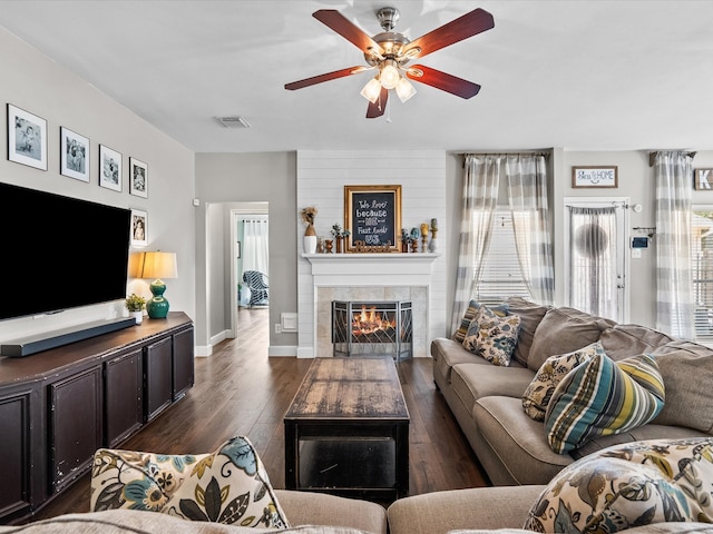 living room with baseboards, visible vents, a ceiling fan, dark wood-style floors, and a fireplace