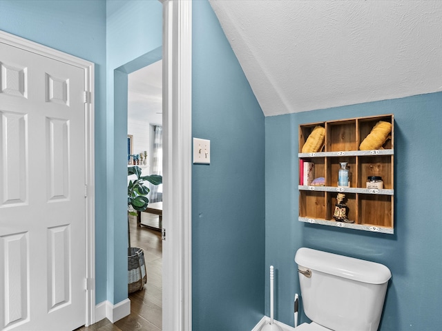 bathroom with lofted ceiling, a textured ceiling, wood finished floors, and toilet