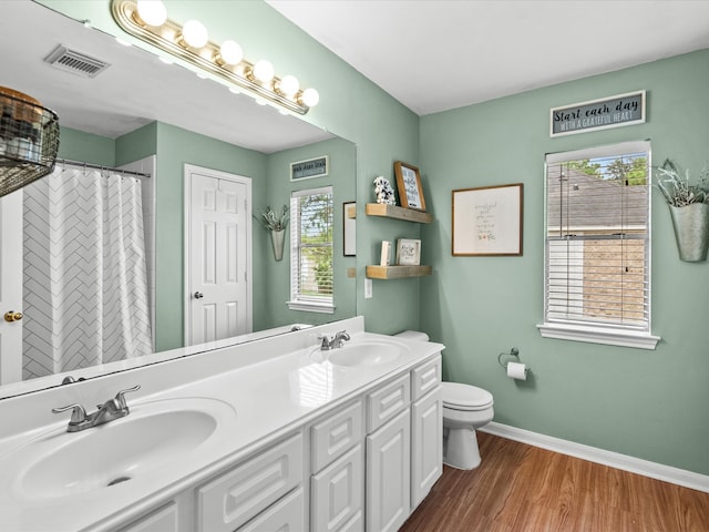 bathroom featuring baseboards, visible vents, a sink, and wood finished floors