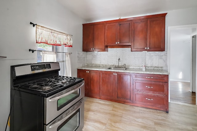 kitchen with backsplash, stainless steel gas range, and sink