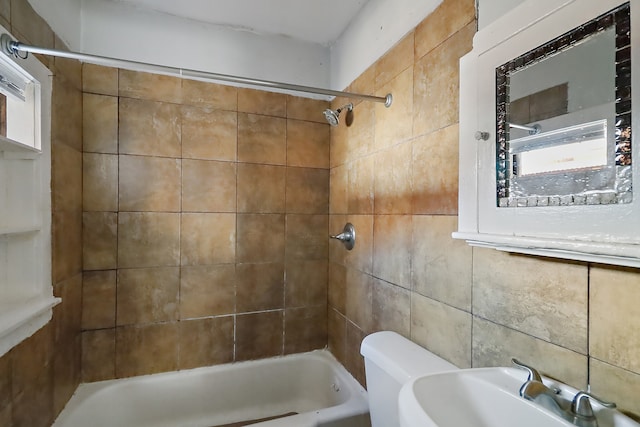 full bathroom featuring tiled shower / bath, sink, toilet, and a healthy amount of sunlight