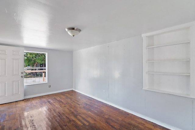 spare room with built in features and hardwood / wood-style floors