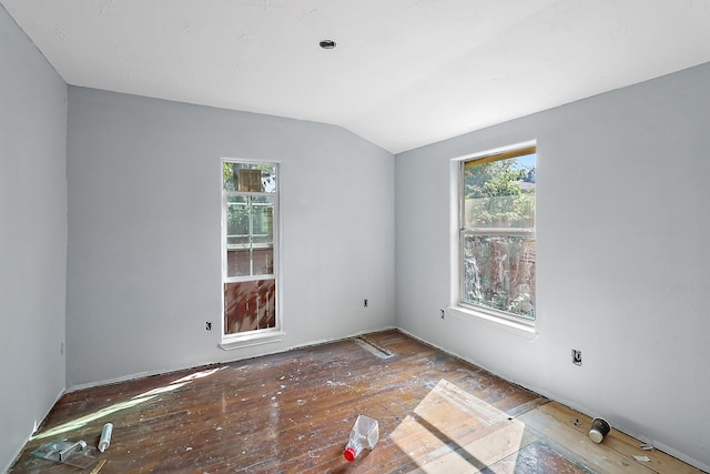 spare room with vaulted ceiling, hardwood / wood-style flooring, and a healthy amount of sunlight