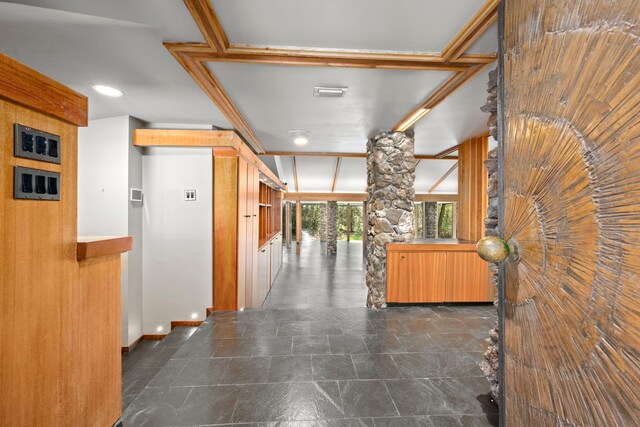 hallway featuring stone finish floor, decorative columns, visible vents, and elevator