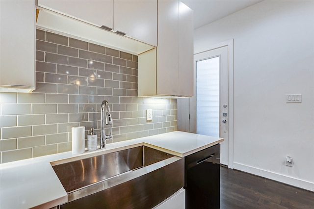 kitchen featuring decorative backsplash, black dishwasher, dark wood-type flooring, and sink